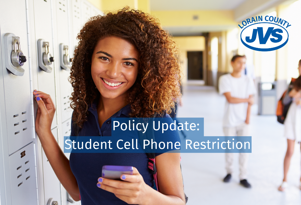 Girl with a cell phone in the hallway leaning on a locker. 
