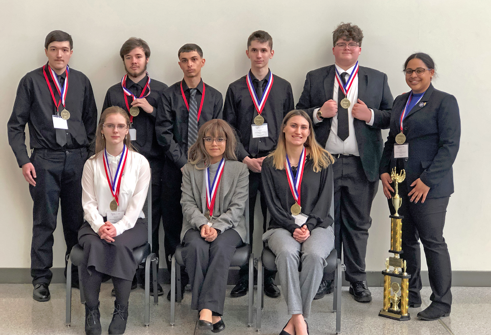 Nine Lorain County JVS students stand and sit smiling with their medals and tropheys at the BPA State competition