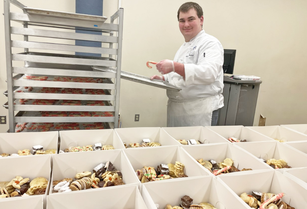 Male Bakery and Pastry Arts student placed candy cane cookies in the cookie boxes
