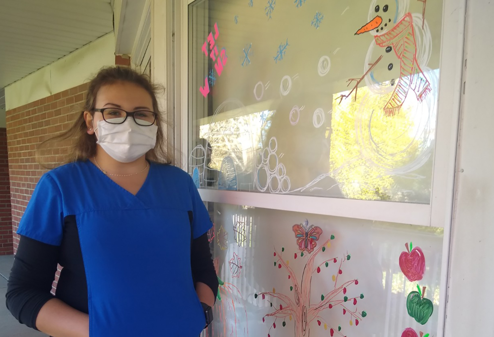 McKayla Ortiz stands by her painted window at O'Neill Healthcare Center