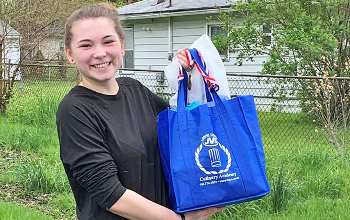 Megan Rataj (Clearview), scholarship recipient, smiles with her JVS Class of 2020 yard sign and culinary arts gift bag 