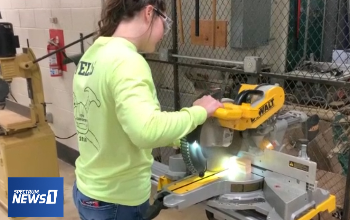 Female carpentry student runs saw in lab