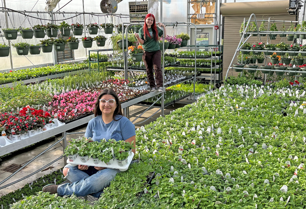 Landscape and Greenhouse Management students, Kirby Herrera (Columbia) and Alea Stewart (Wellington) smile in the LCJVS greenhouse ahead of their annual spring sales.