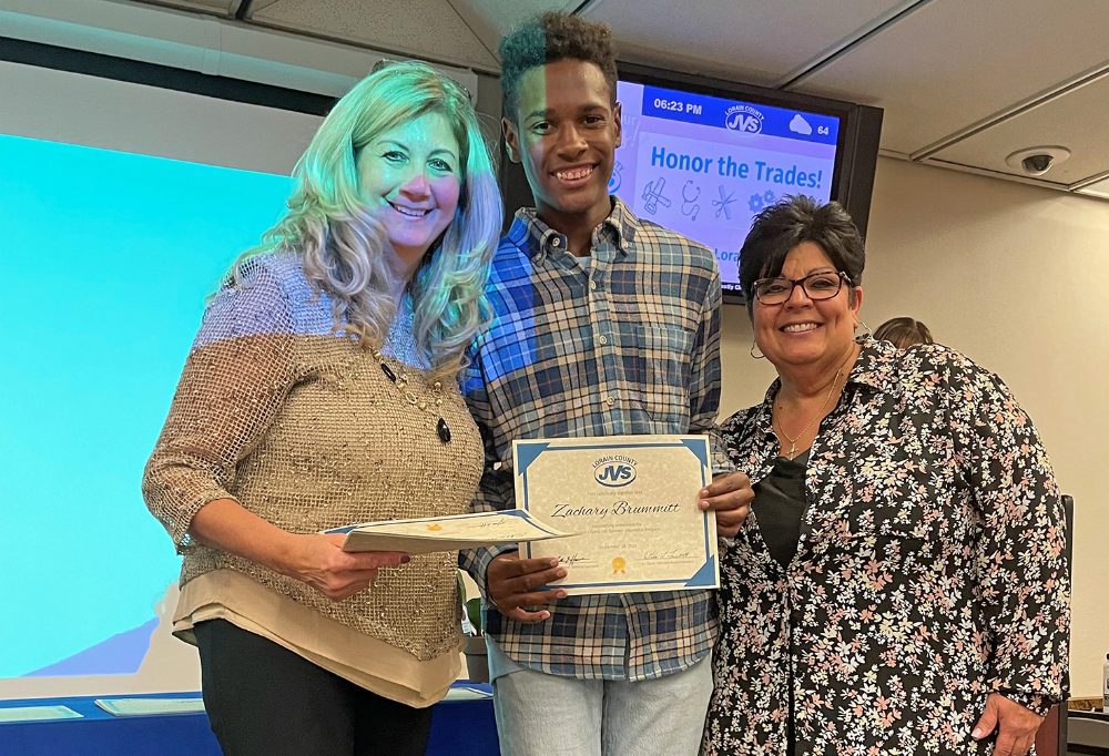 Zachary Brummitt (middle), Cosmetology senior (Clearview) smiles with instructors Jean Sarconi and Sandra Hernandez after receiving his certificate of completion at the LCJVS Summer Internship Celebration.