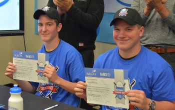 Two male students smile with their letters of intent